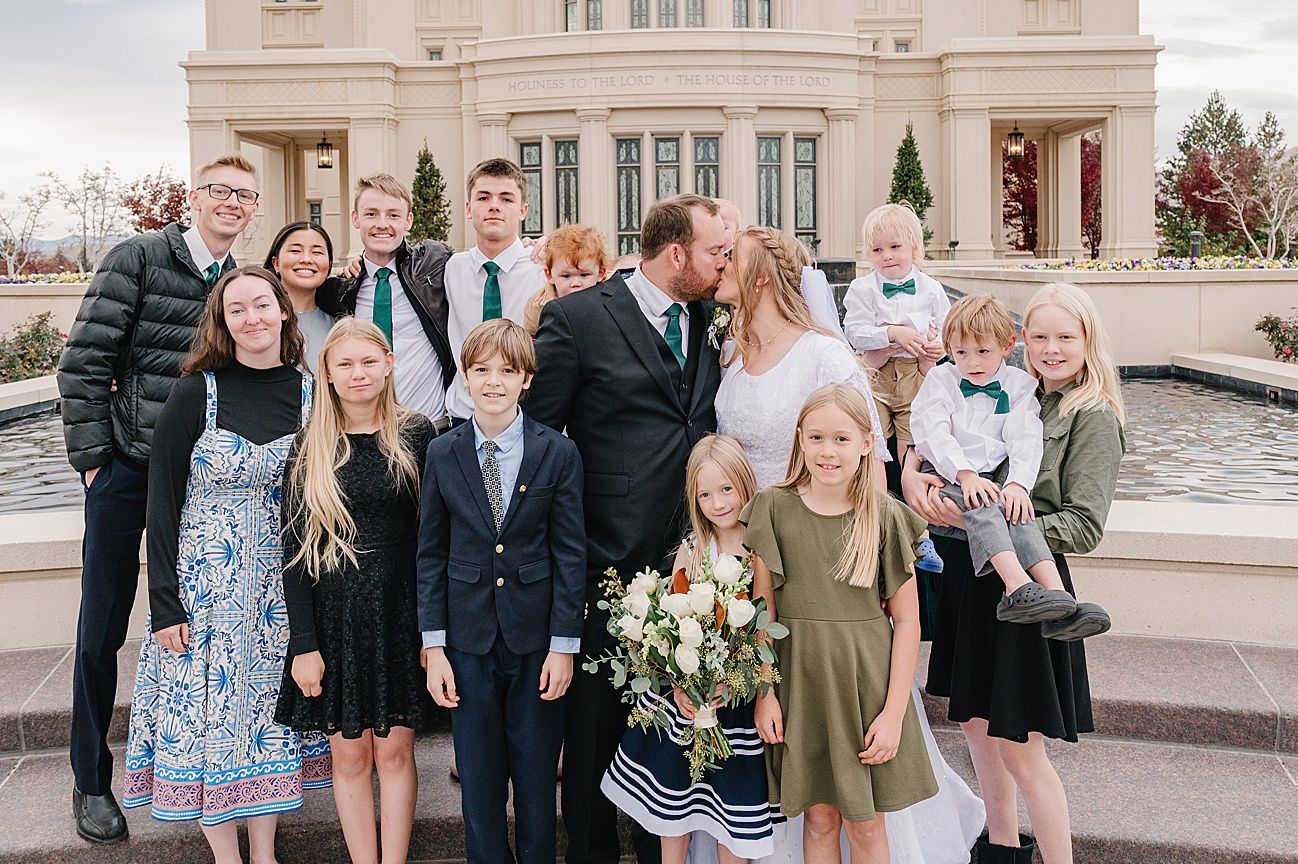 A group gathers for a formal photo outside a grand temple building with beige stone architecture and tall windows.