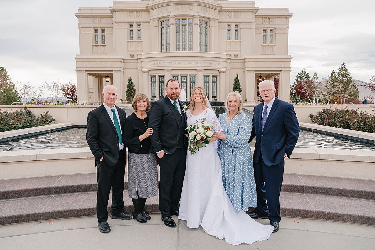 Wedding party gathers on elegant stone terrace steps for formal group photos during outdoor celebration.