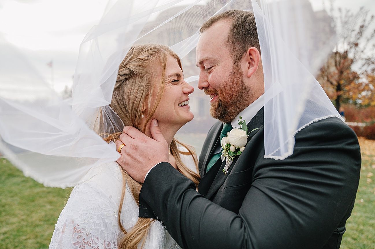 Romantic wedding portraits with flowing veil captured during an intimate outdoor moment.