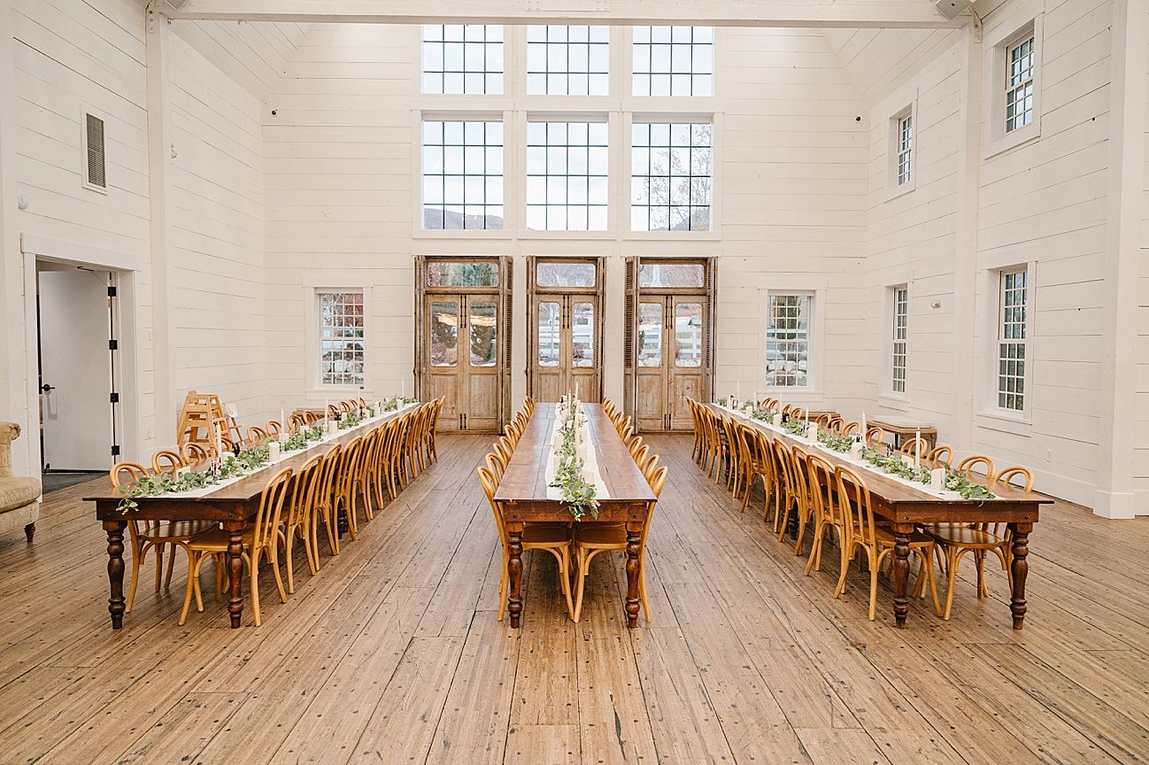 Long wooden dining tables and chairs line the bright white interior of a historic meeting house or church hall.