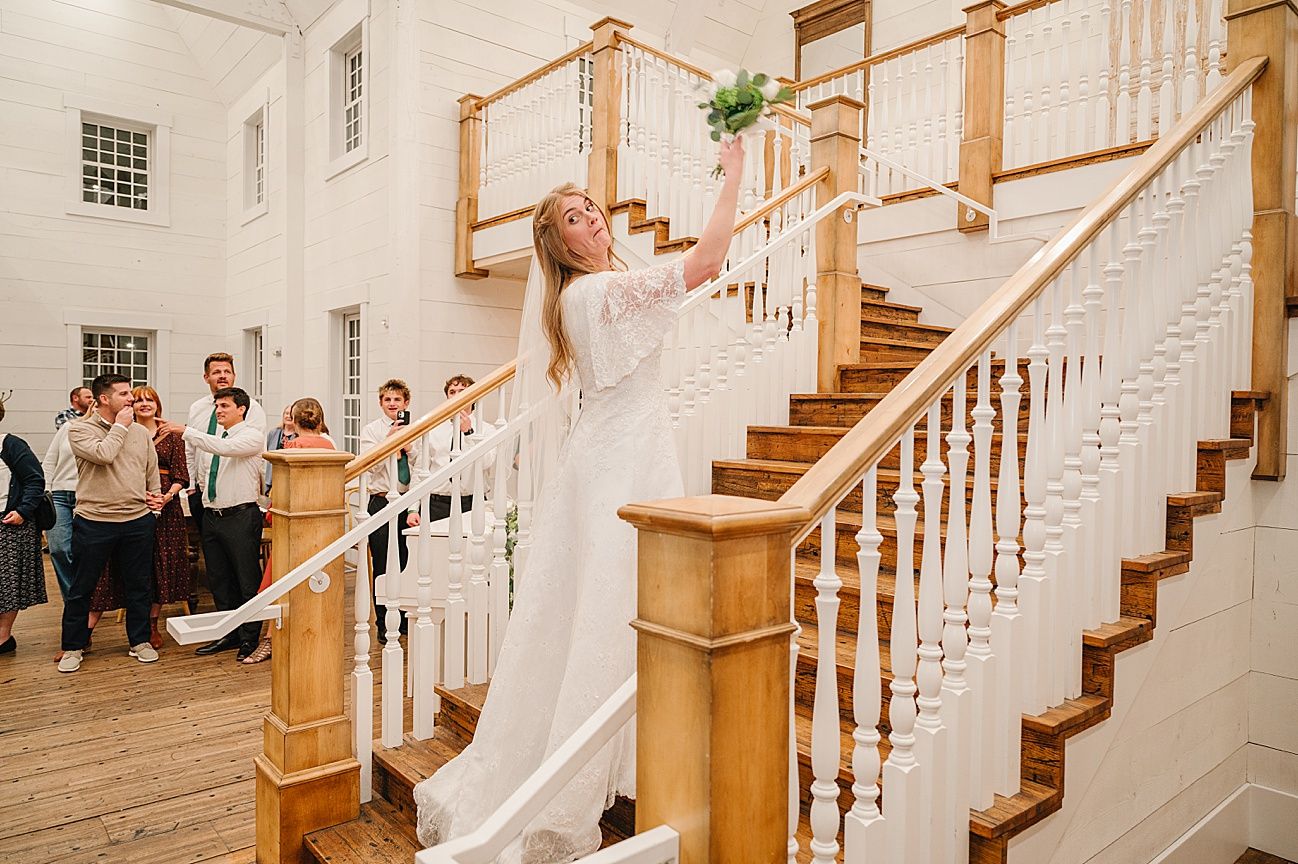Elegant wooden staircase with white railings in a wedding venue surrounded by guests.