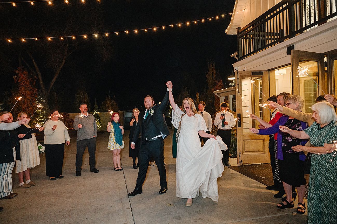 Outdoor wedding celebration under warm string lights with guests forming lines for a dance.