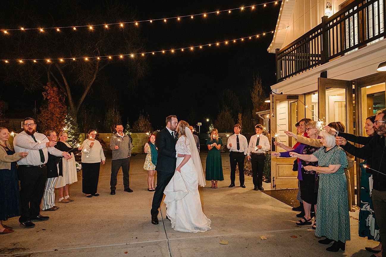String lights illuminate an outdoor wedding venue at night with guests gathered around.
