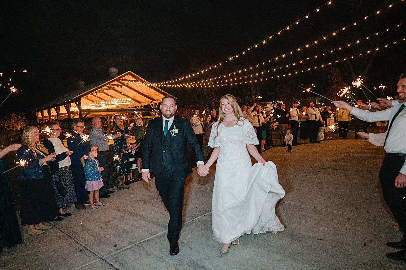 Wedding guests dance under twinkling string lights at an evening outdoor reception celebration.