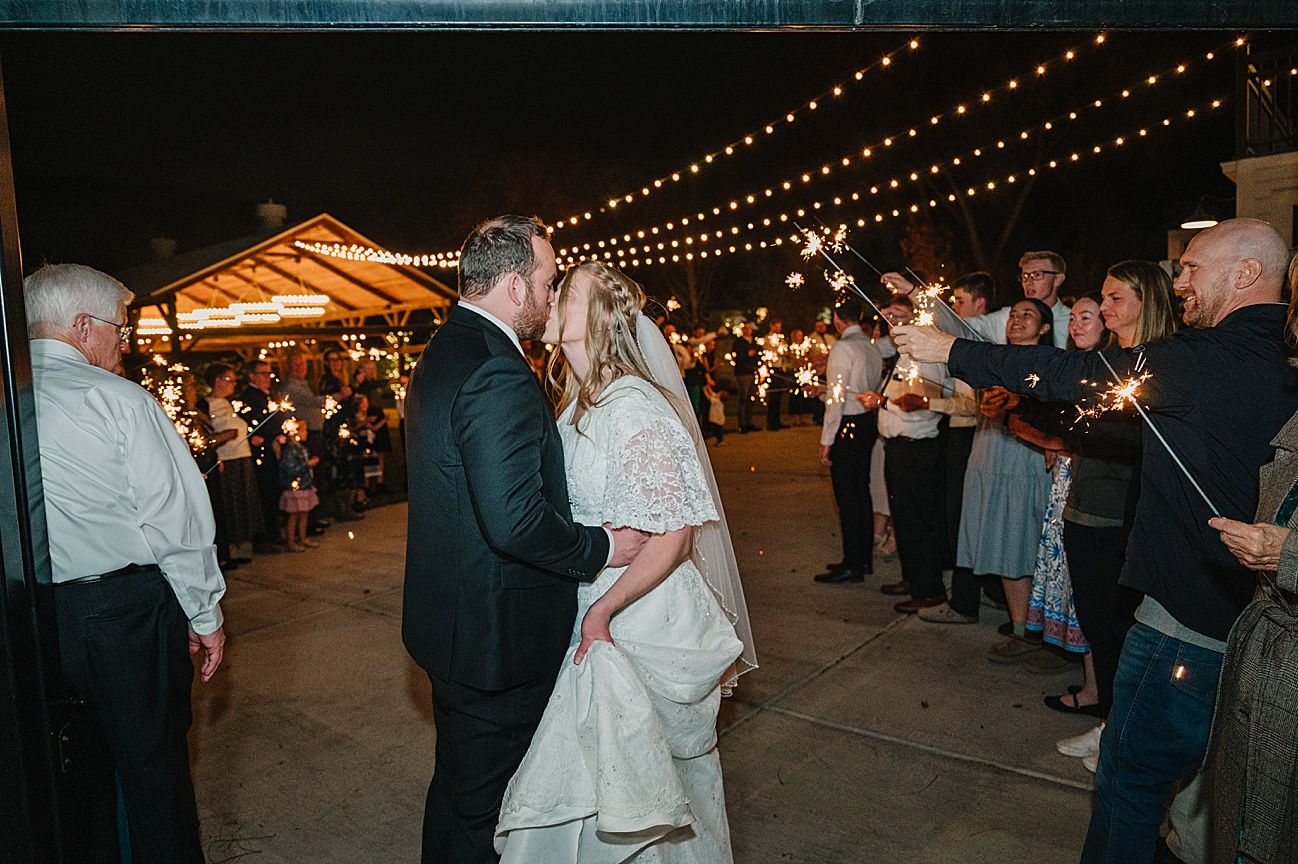 Guests dance under romantic string lights at an evening outdoor wedding reception.