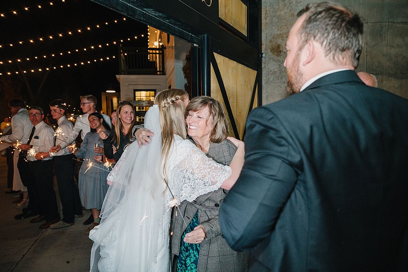 Wedding guests dancing together on a dimly lit dance floor with string lights overhead during an evening reception celebration.
