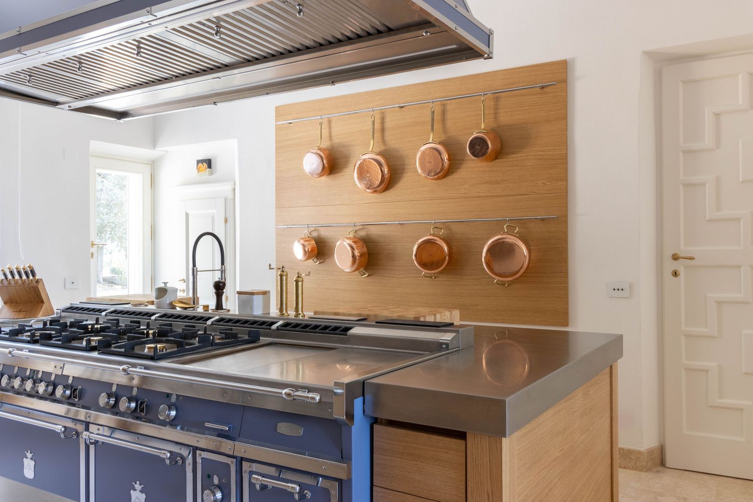 Luxury commercial property photographer in Tuscany, Italy. Modern kitchen interior with light wood cabinets, copper pots on display.