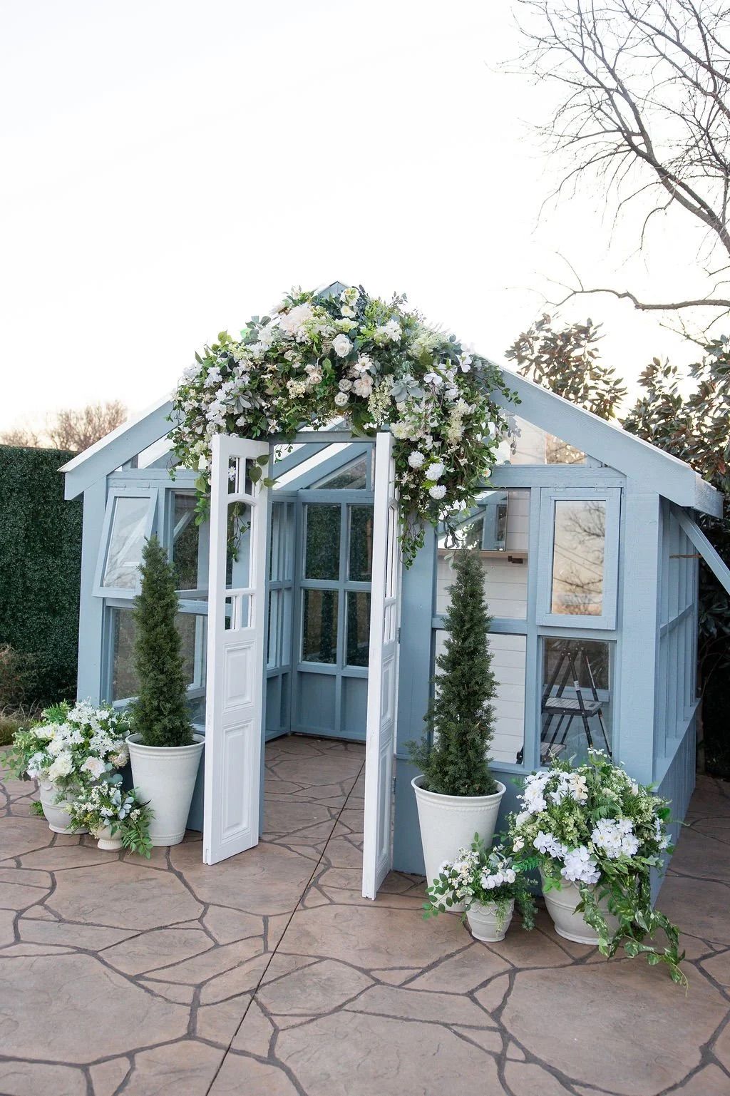 White ceramic planter with cascading white flowers and green foliage creates an elegant garden display on stone patio.