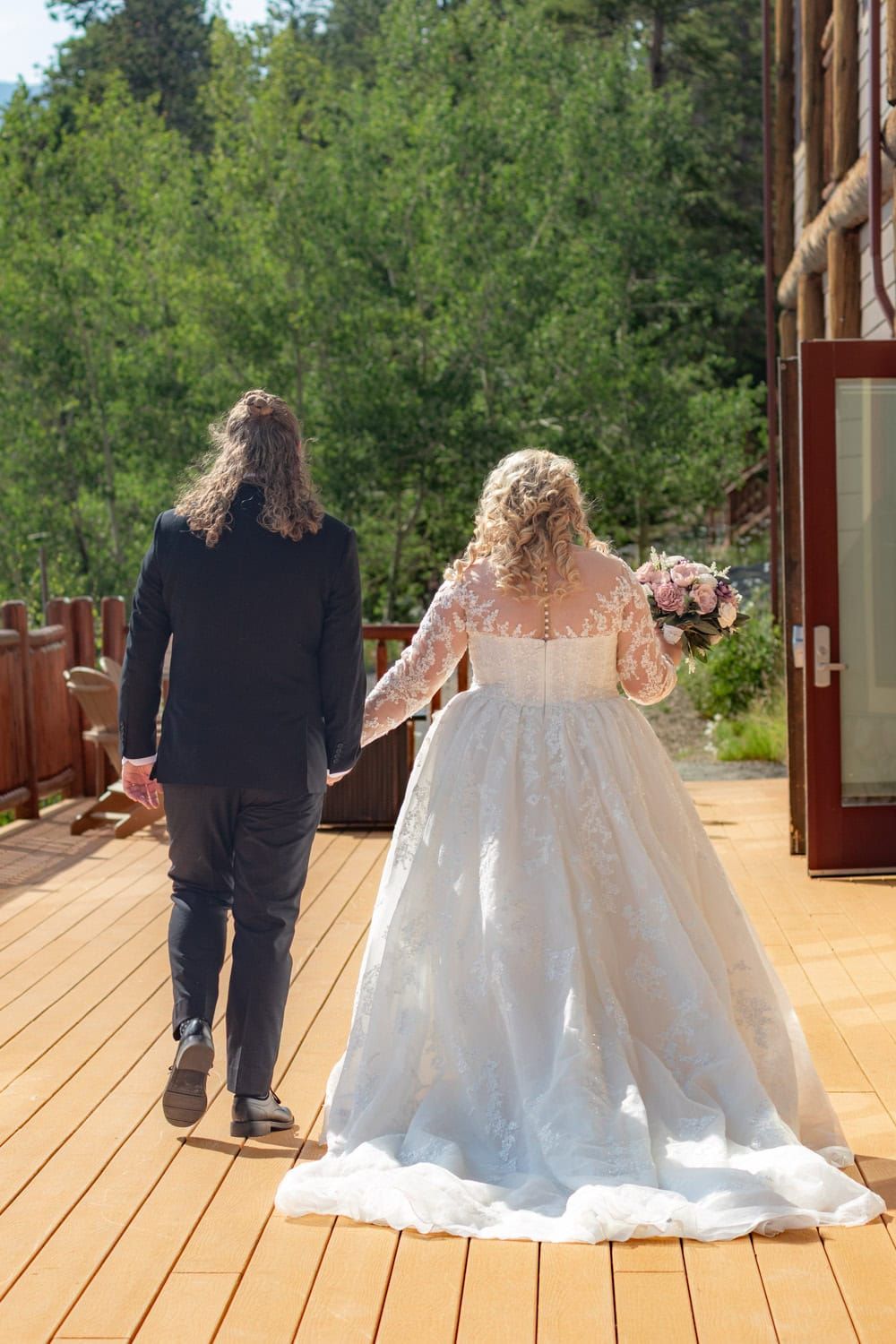 A wedding dress train flowing across a wooden deck with trees in the background.