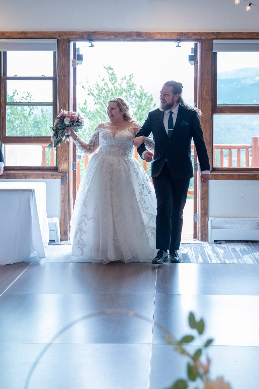 A wedding couple dancing in an elegant venue with large windows and mountain views.