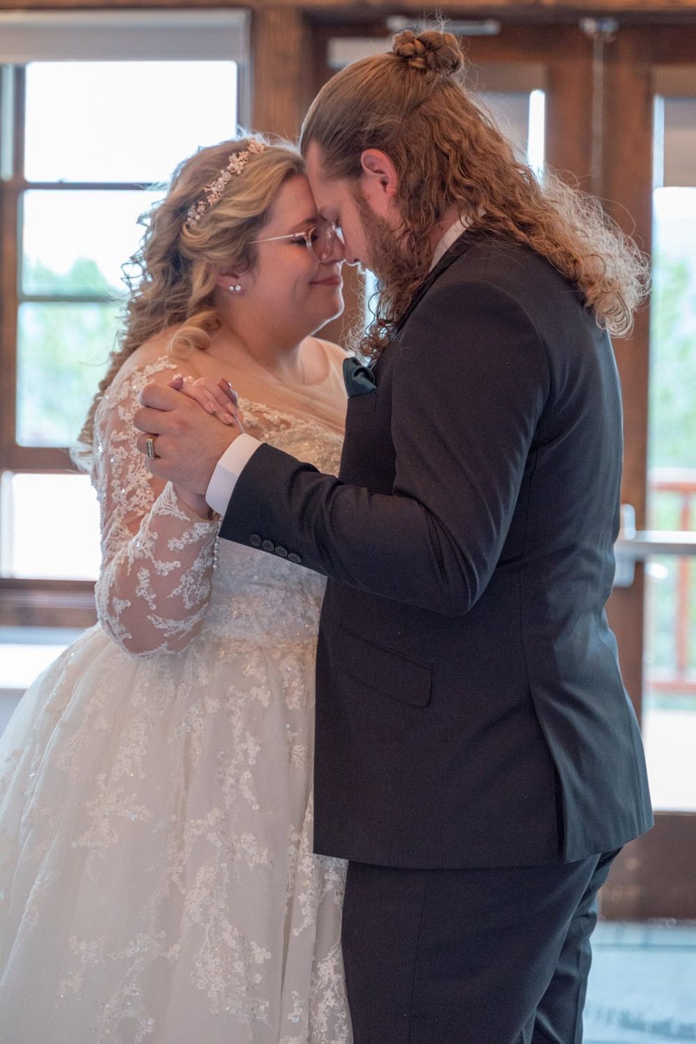 A romantic first dance moment in a rustic wooden venue with natural lighting.