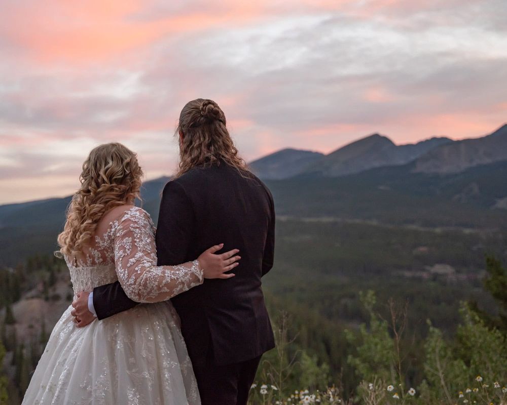 A couple embracing against a sunset mountain backdrop during their wedding celebration.
