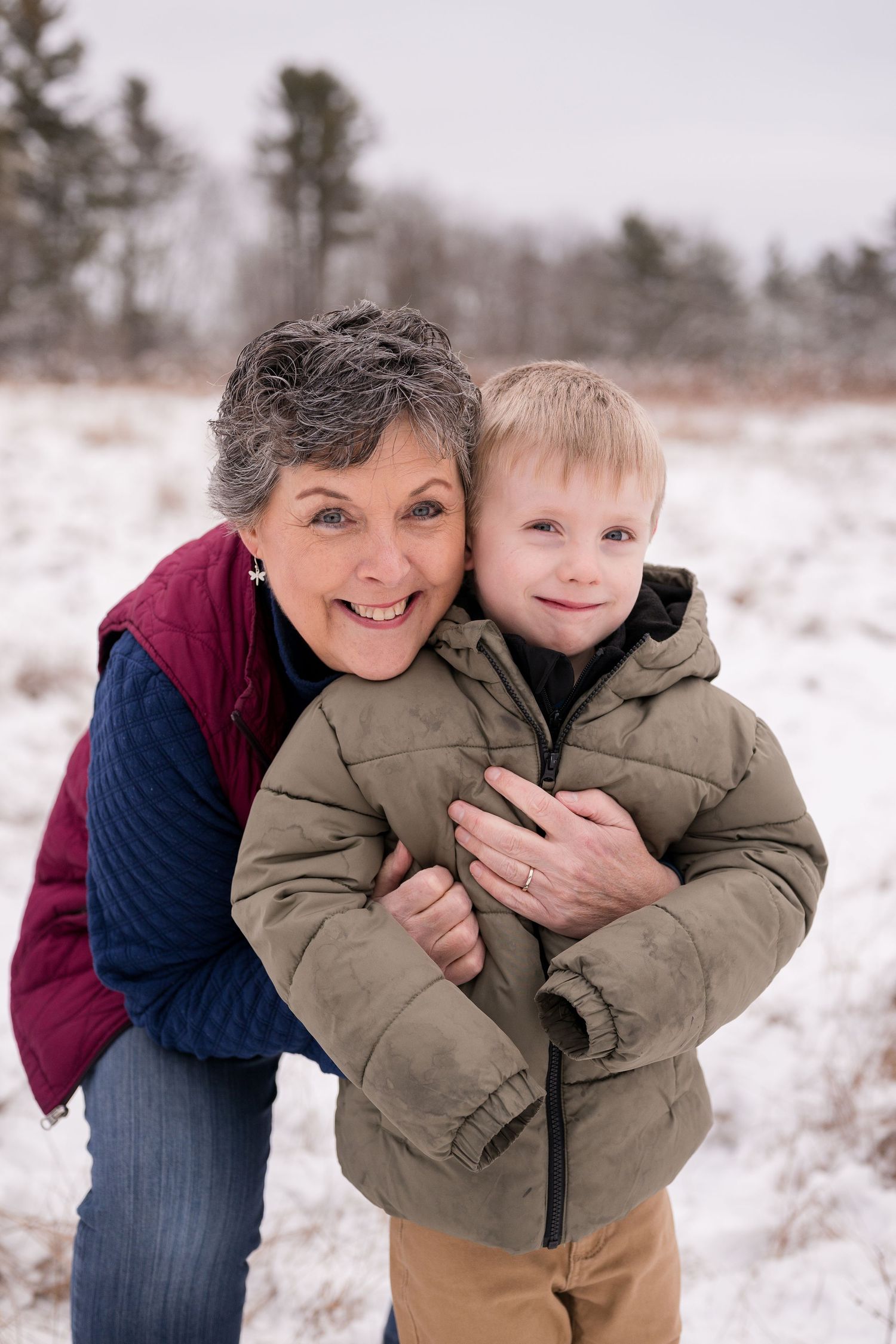 Playful winter photo session in snow covered field with pine trees.