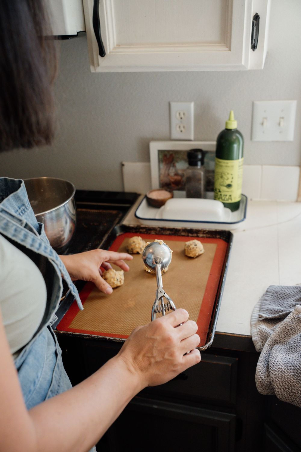 A sequence of hands rolling sushi on a dark countertop with a bottle and kitchen items visible in the background.