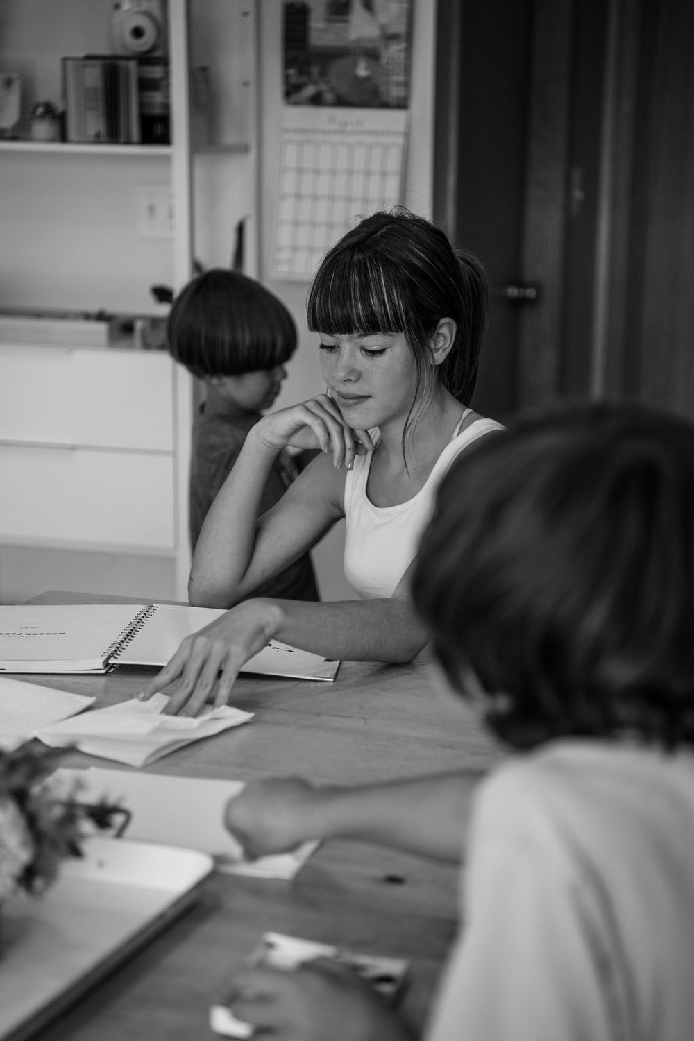 Students working together at a table with papers and study materials in black and white.