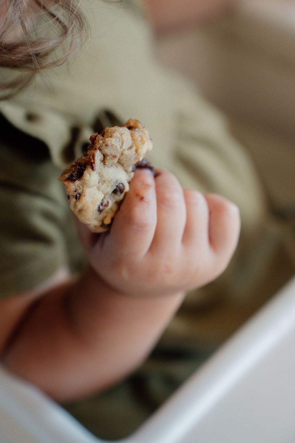 Close-up sequence of tiny toes with cookie crumbs showing progressive eating of a chocolate chip cookie.