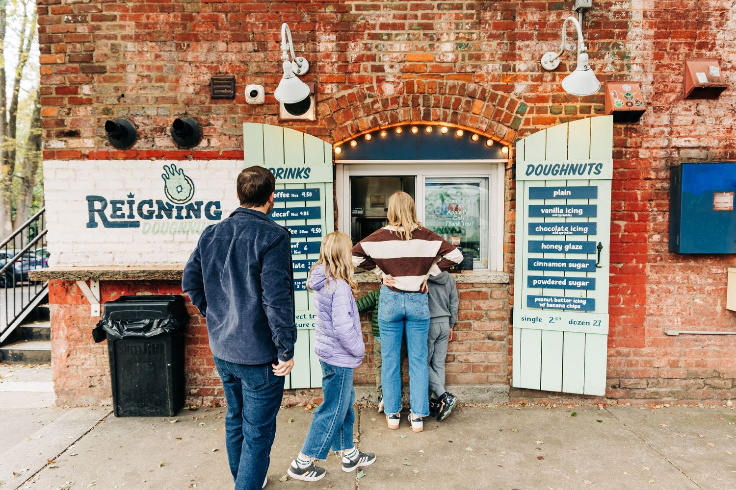 A view of an industrial brick space with exposed walls and scattered people in a casual setting waiting in line for doughnuts in Charlotte.