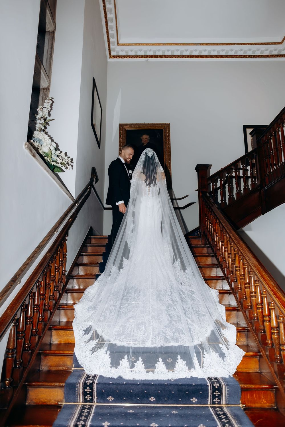 A flowing white wedding veil cascades down a wooden staircase with ornate railing in a series of elegant photos.