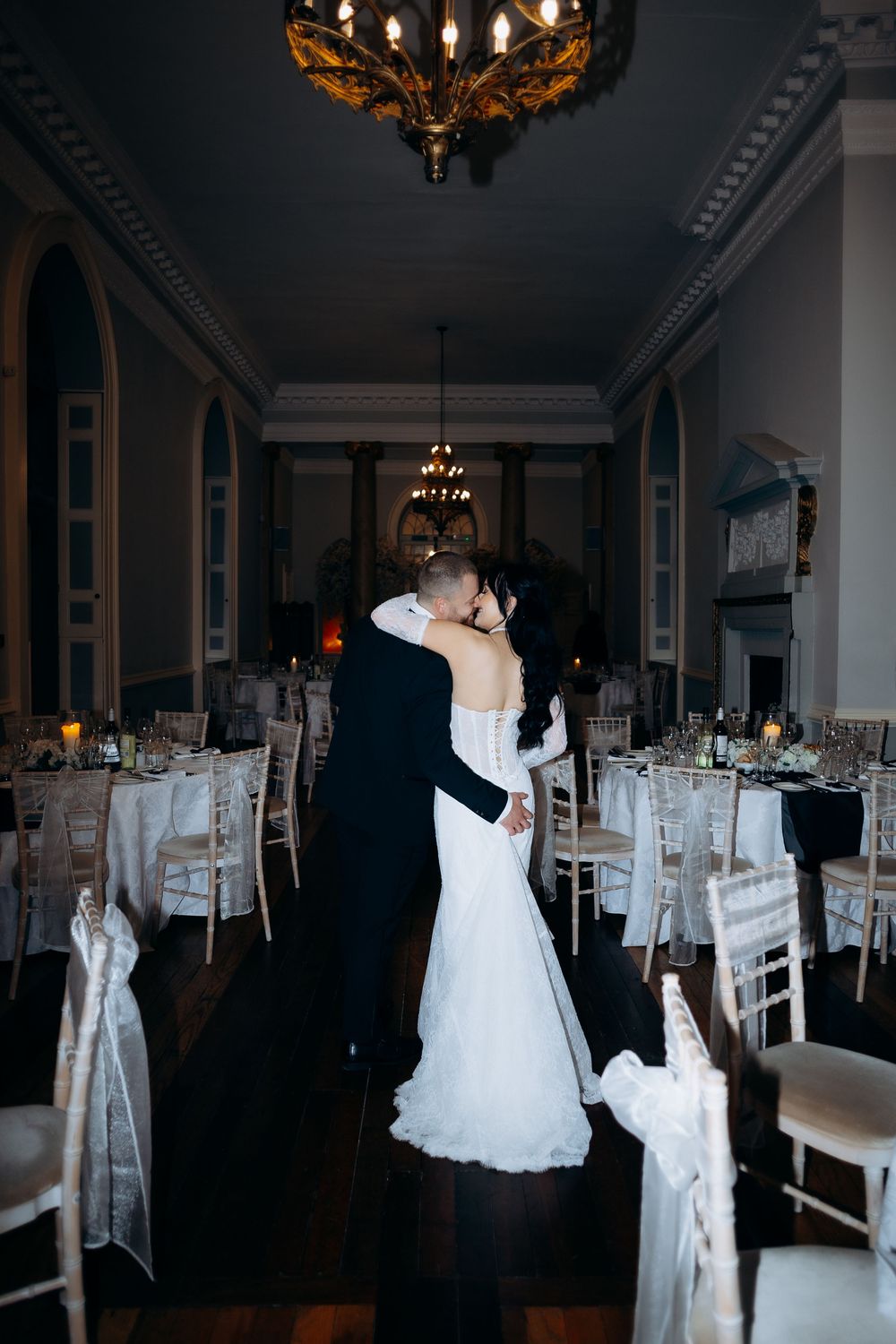 Elegant wedding reception venue with white chair covers and crystal chandeliers set for an evening celebration.
