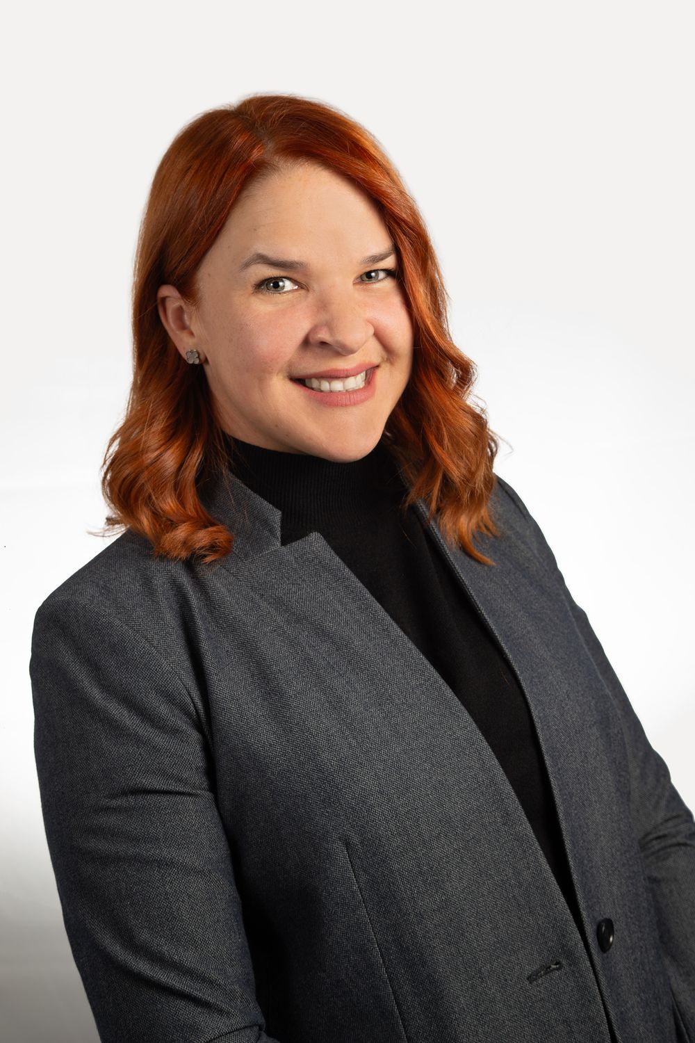 Professional headshot of a red headed woman in a gray jacket in NYC