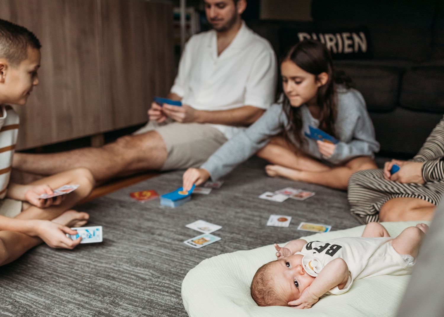 People playing a card game together at a wooden table, viewed from multiple angles.