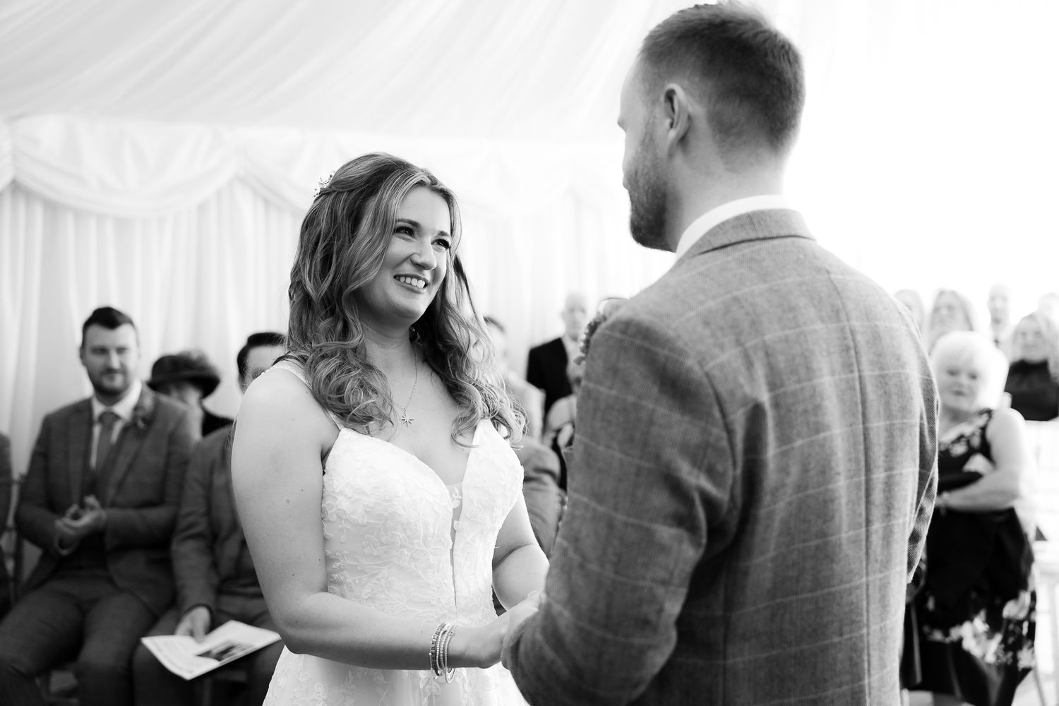 A joyful wedding celebration with guests dancing and mingling under an elegant white tent.