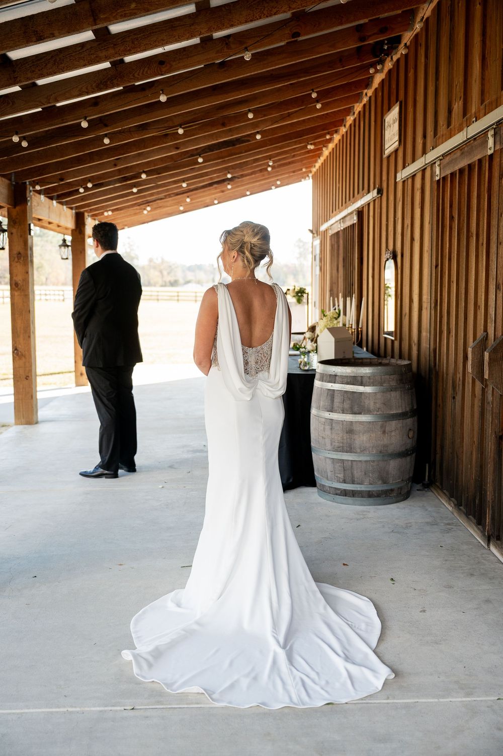 Wedding couple sharing intimate moment in rustic barn with wooden beams and barrel decor.