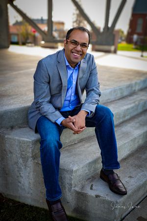 Professional portrait series showing a person in a gray suit and blue shirt sitting on concrete steps outdoors.