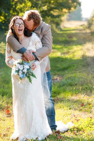 A couple shares joyful moments in a sun-drenched meadow during their rustic outdoor wedding photoshoot.