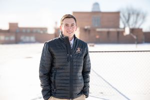 Professional headshot portrait of someone wearing a black puffer jacket against a snowy winter background.