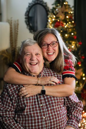 A heartwarming sequence of candid embraces between two people wearing plaid shirts with Christmas decorations in background.