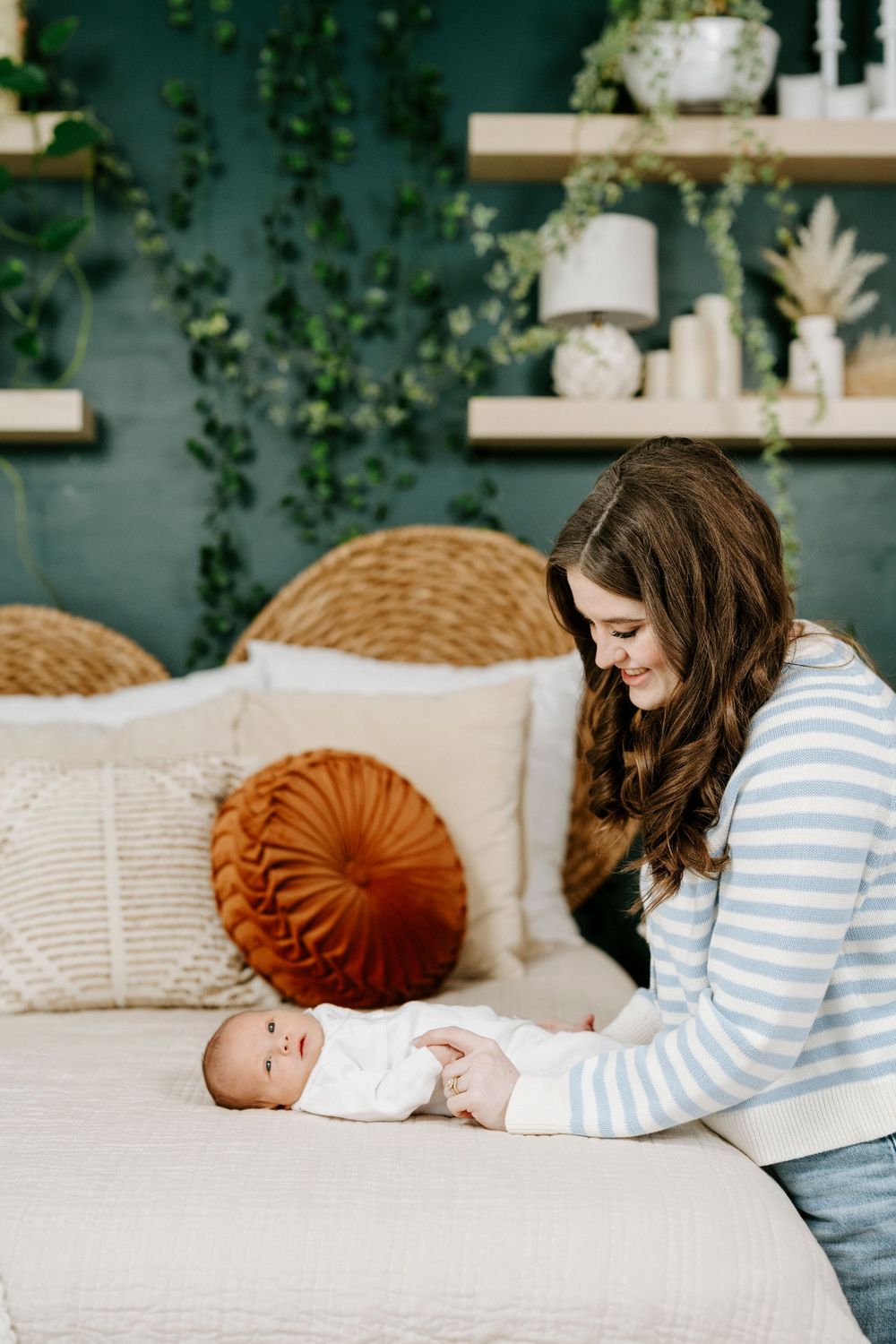 A parent in a striped shirt lies on a cream-colored couch with a small baby, with decorative pillows visible.