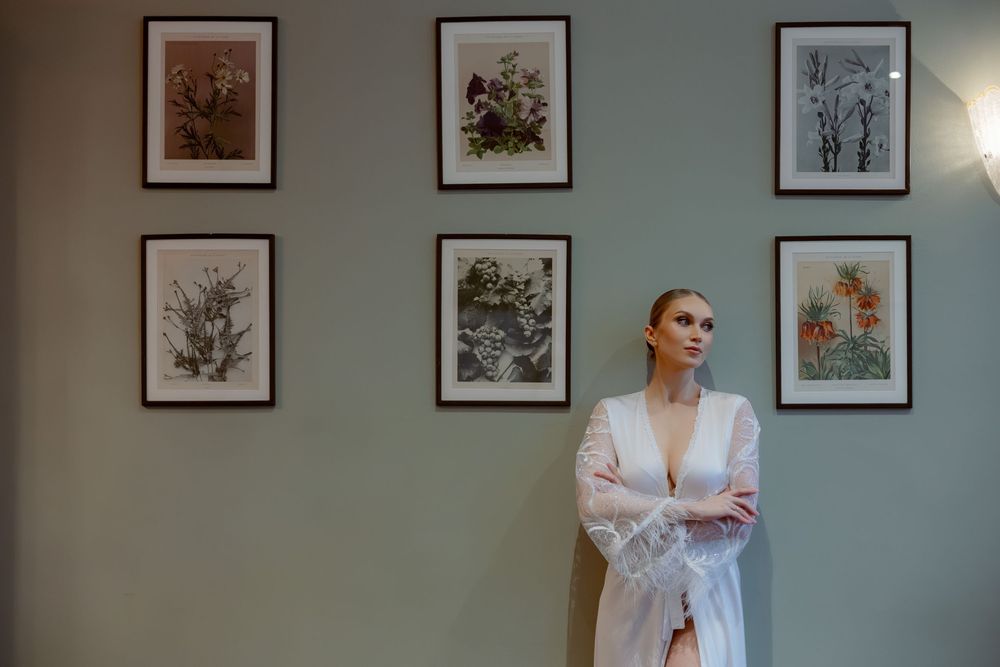 A gallery wall displays framed botanical and nature prints with soft blue-green walls as the backdrop.