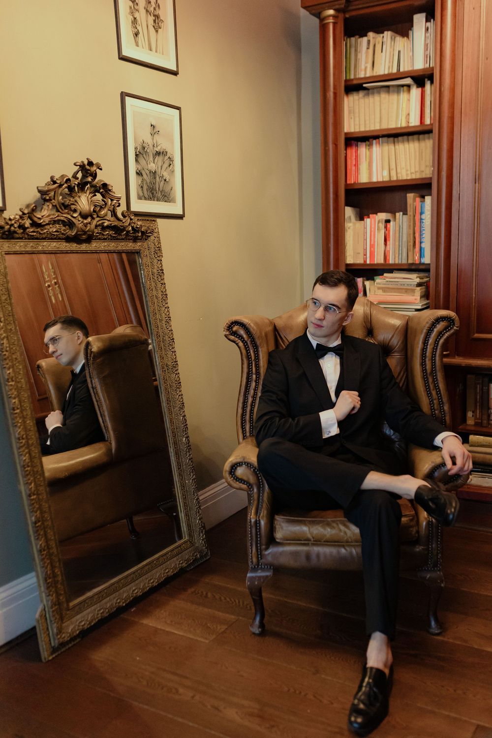 A series of five connected photos showing someone in a dark suit sitting beside an ornate gold frame in a library setting.