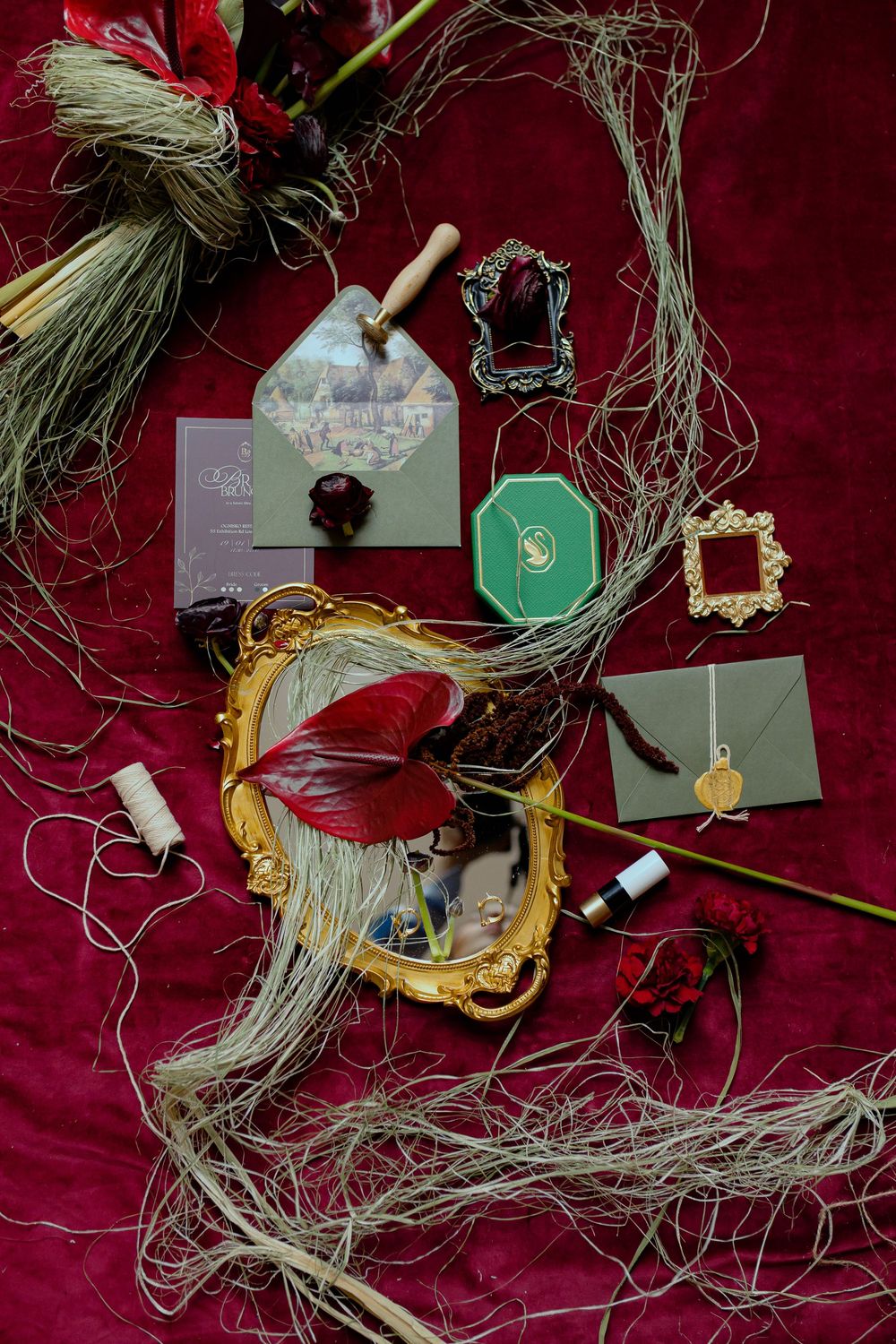 Decorative Christmas ornaments and gift tags arranged on a deep red velvet background with natural straw elements.