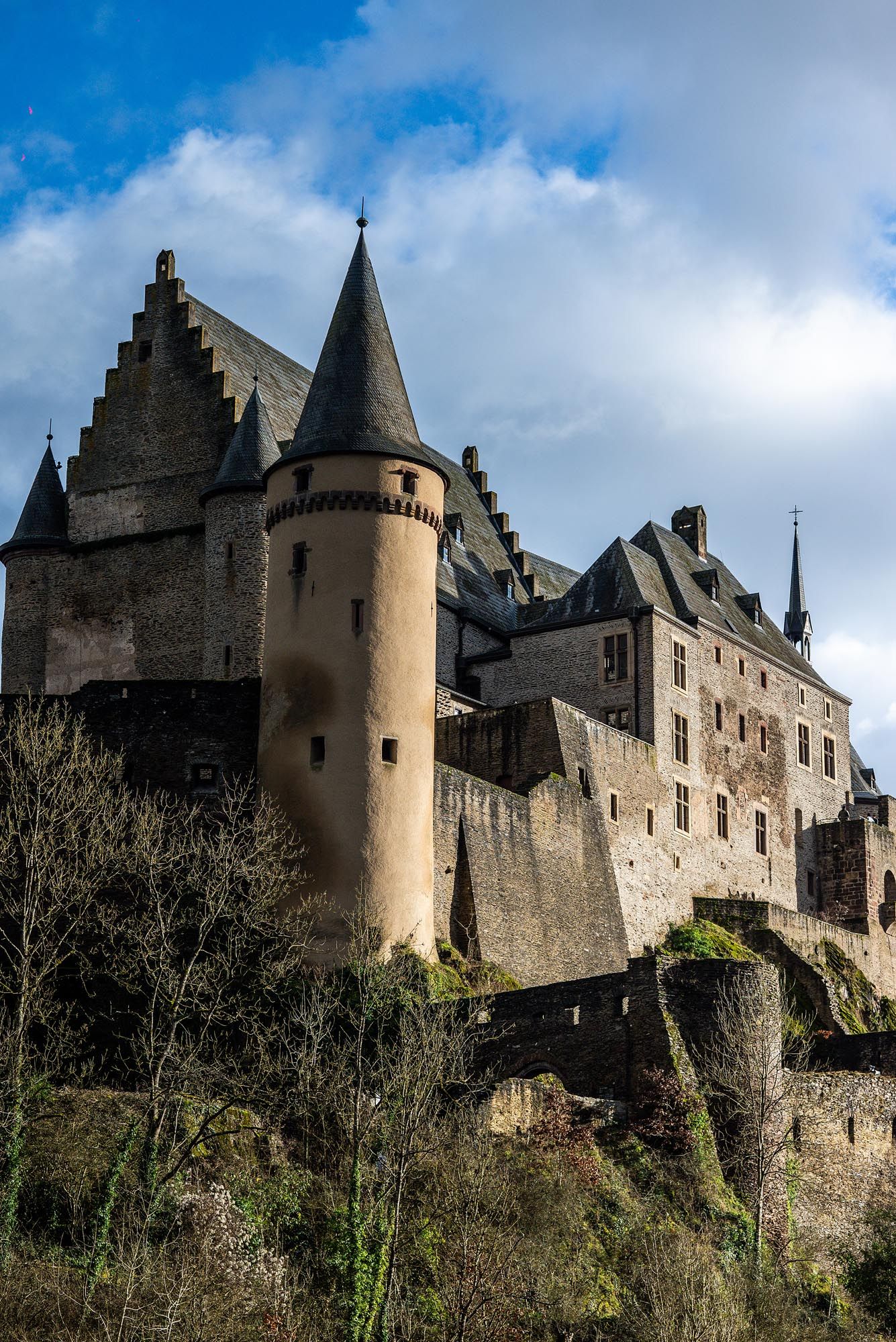 Medieval Vianden Castle perches dramatically on a hilltop in Luxembourg with its distinctive round tower and stepped gables.