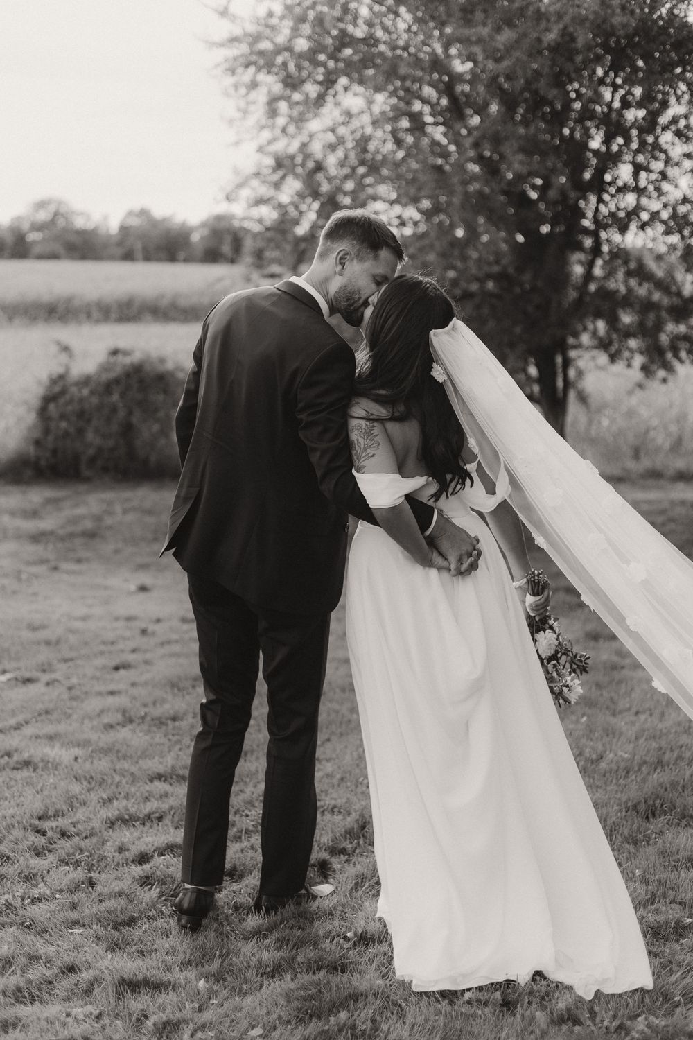 A black and white sequence of wedding photos showing a couple walking together in a field.