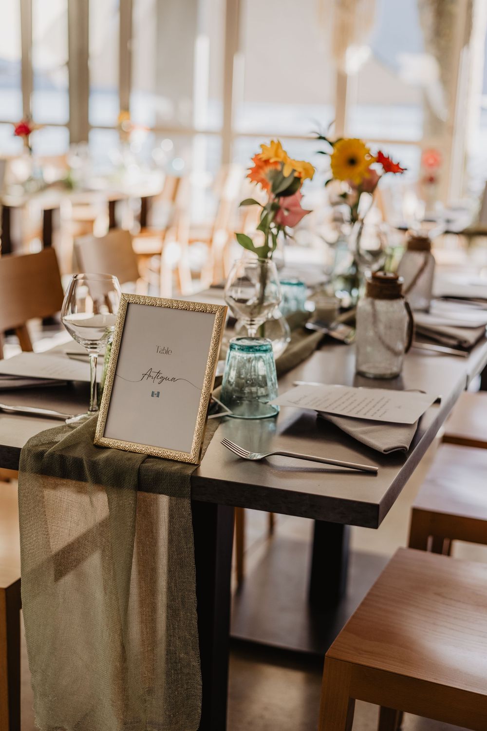 Wedding reception table settings with name cards and simple floral centerpieces.