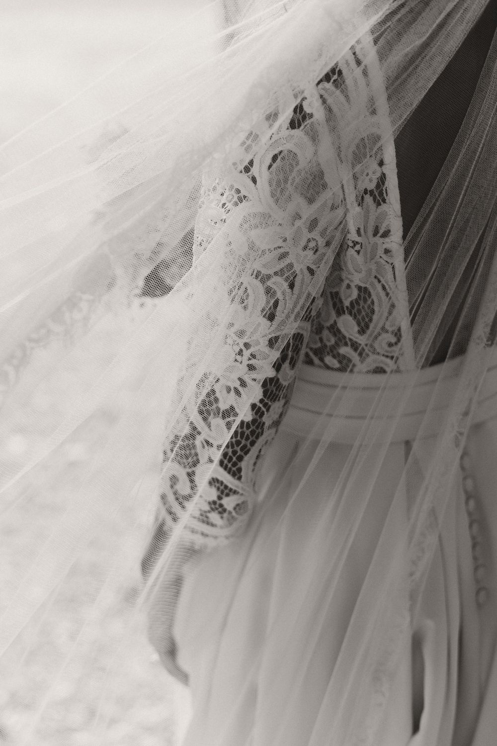 Intricate lace detail of a white wedding veil with delicate embroidered patterns.