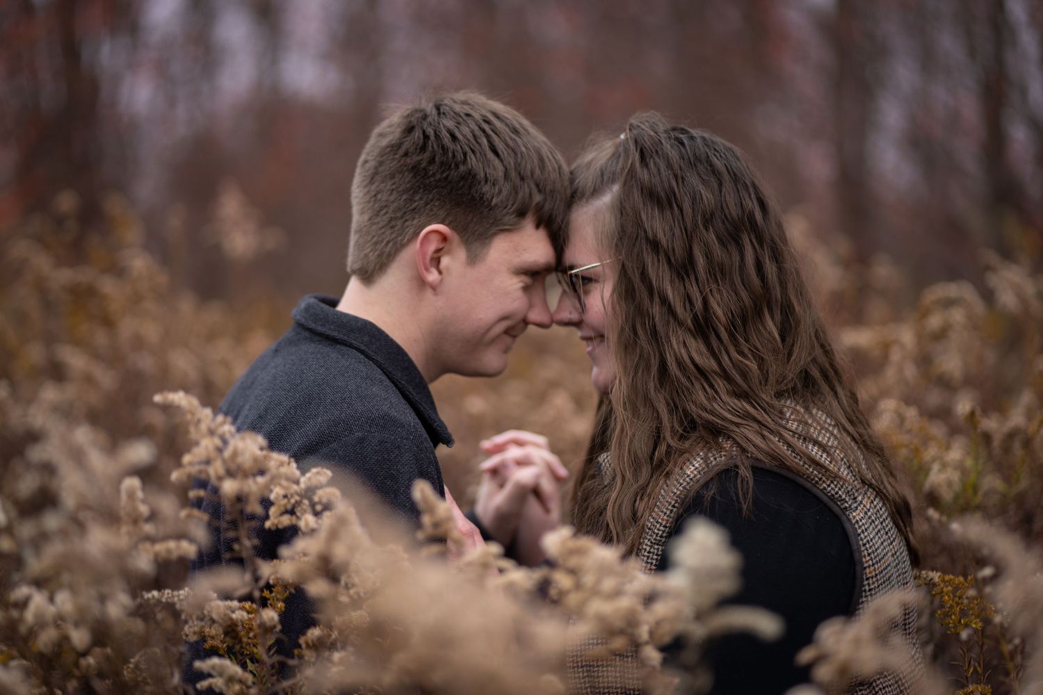 A romantic couple embraces on a wooden bridge in a park setting during a photo session.