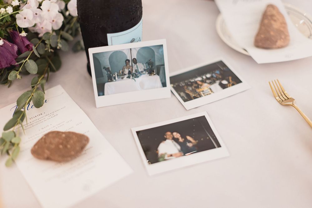 Polaroid photos displayed on a white table with flowers, gold utensils and decorative stones.