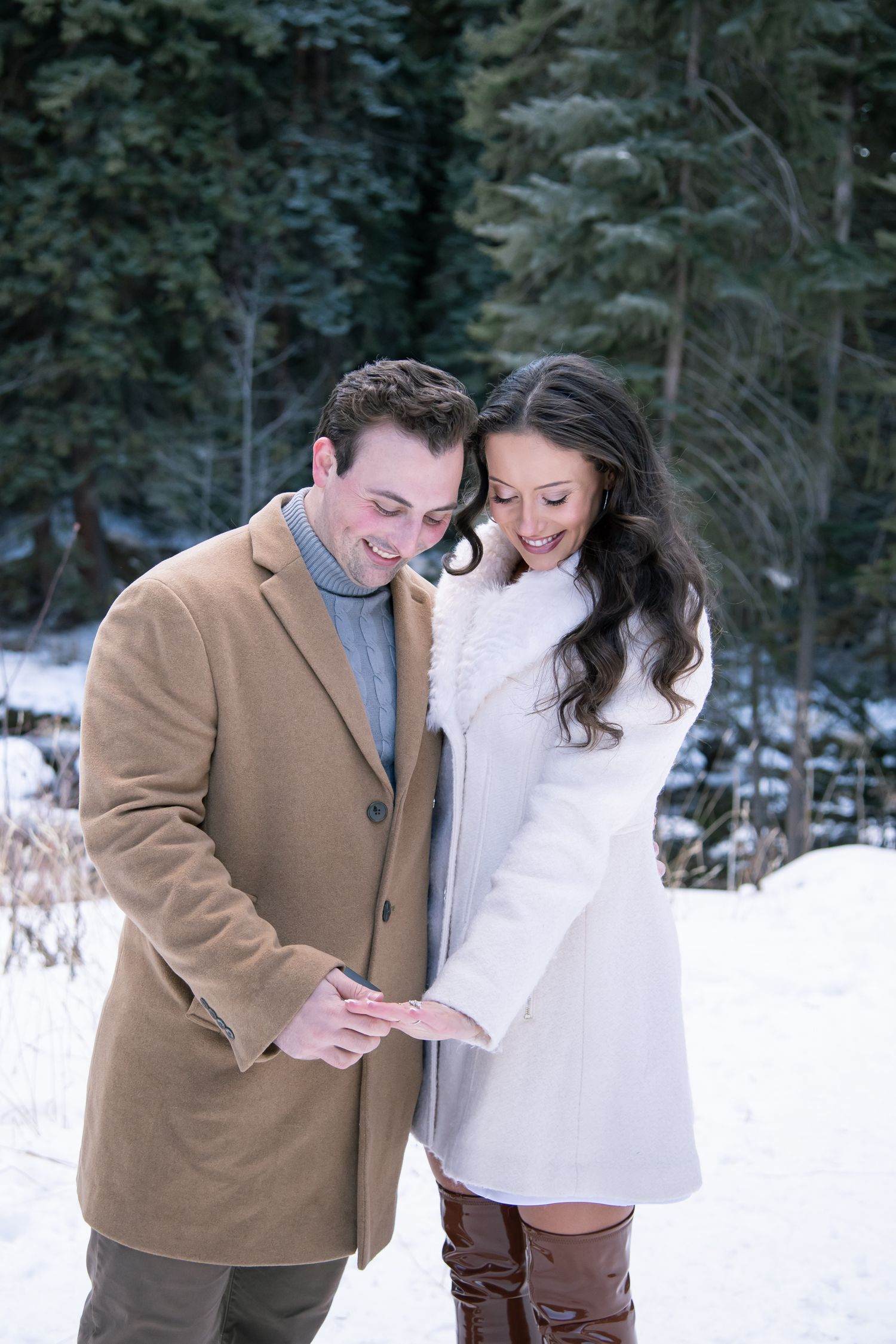 Stylish cute couple gazes at new engagement ring while holding hands during a Vail Colorado winter engagement photo session