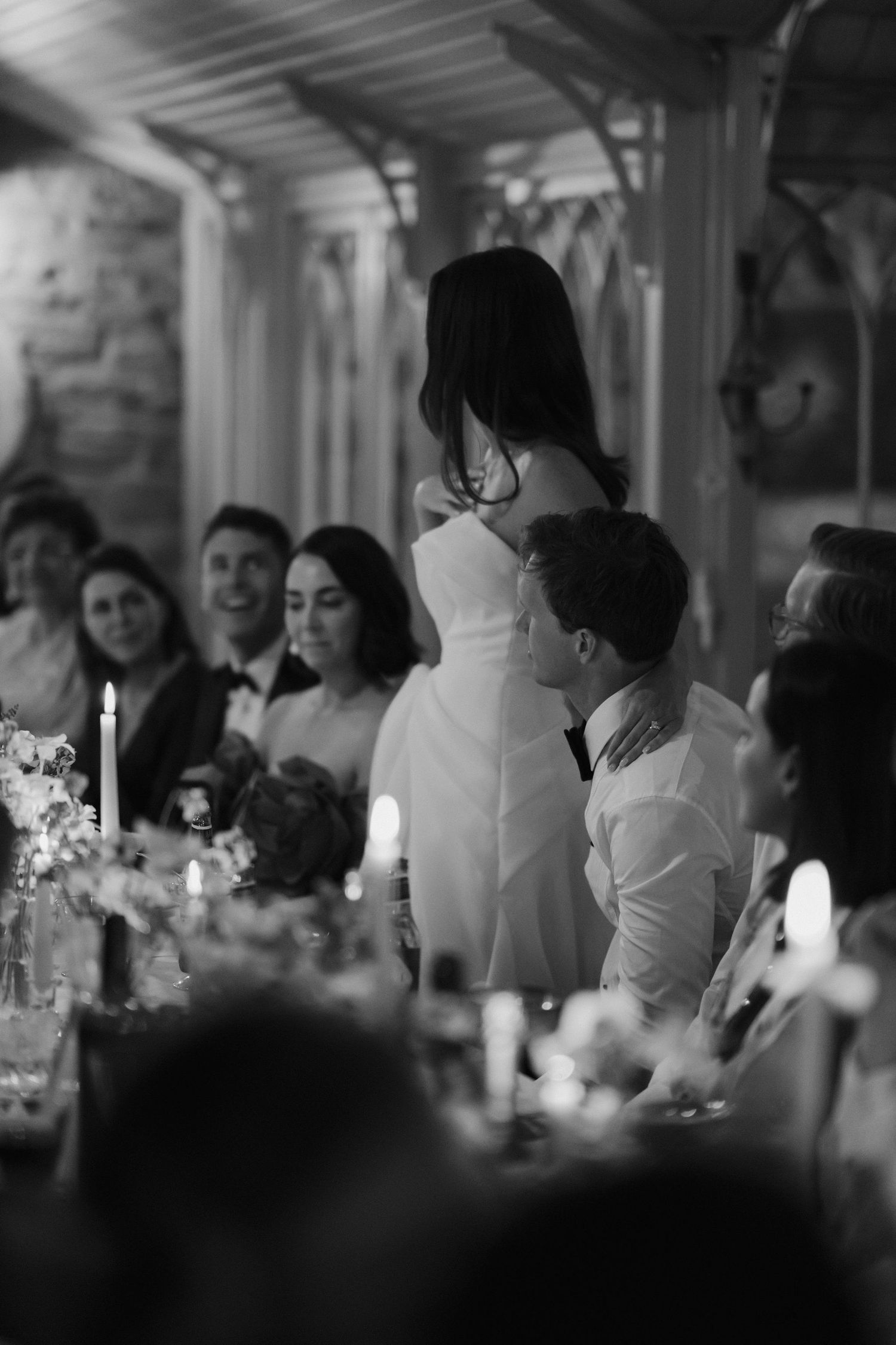 bride giving speech to wedding guests with her arm draped around the grooms neck during the meal at dewsall court in herefordshire