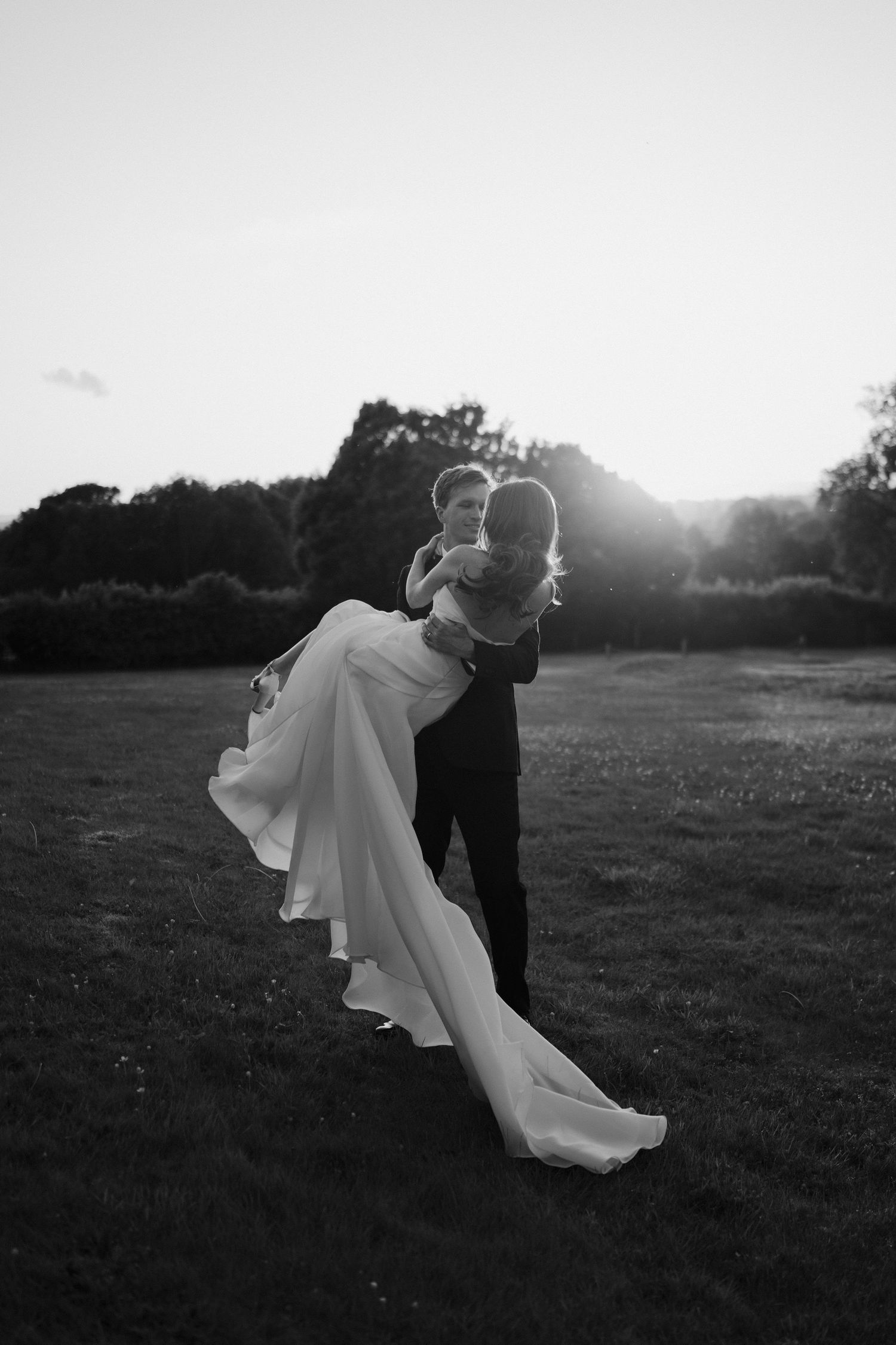 groom sweeping the bride into his arms in the setting sun at dewsall court in herefordshire