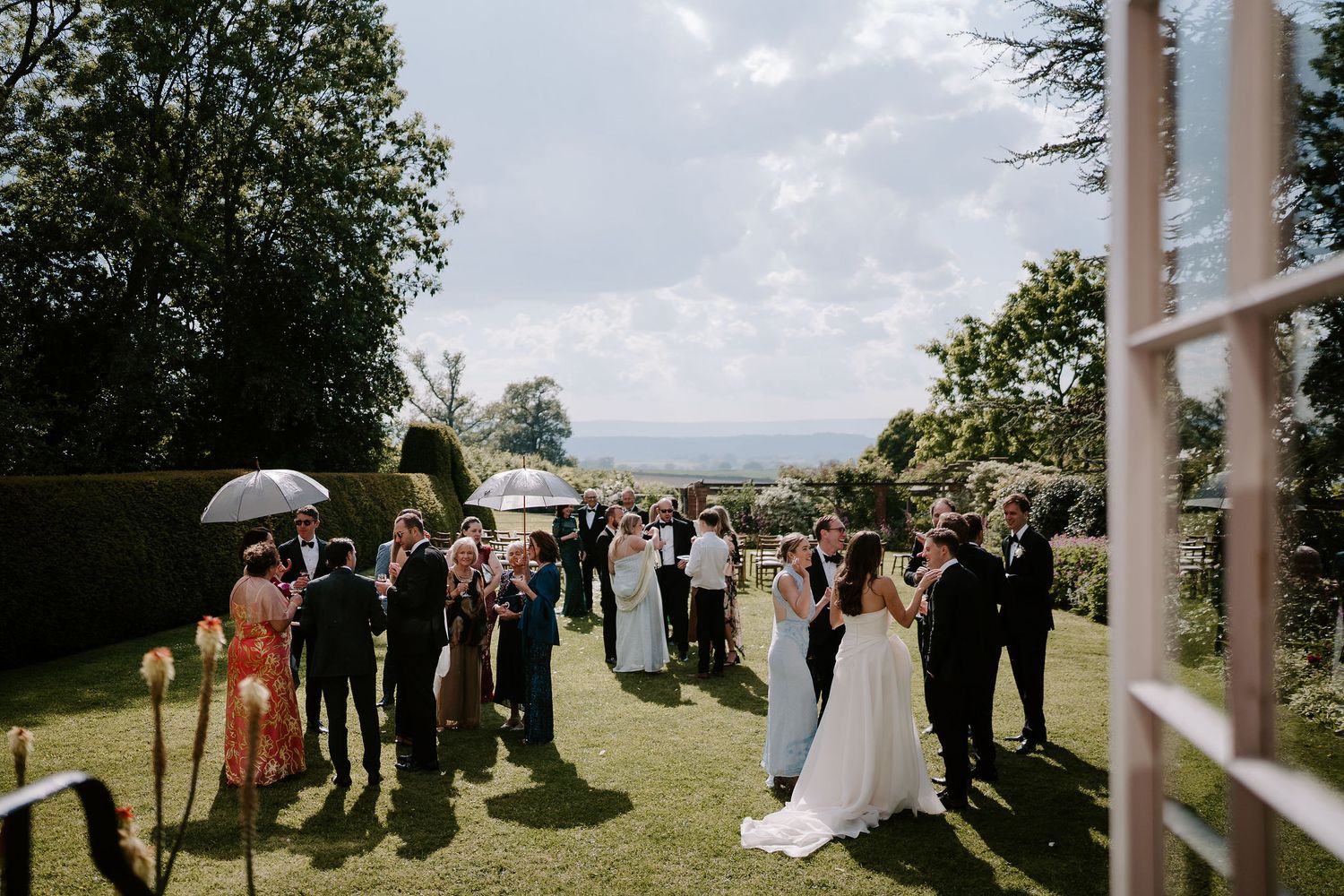 wedding guests enjoying sunshine on the lawn at dewsall court in herefordshire