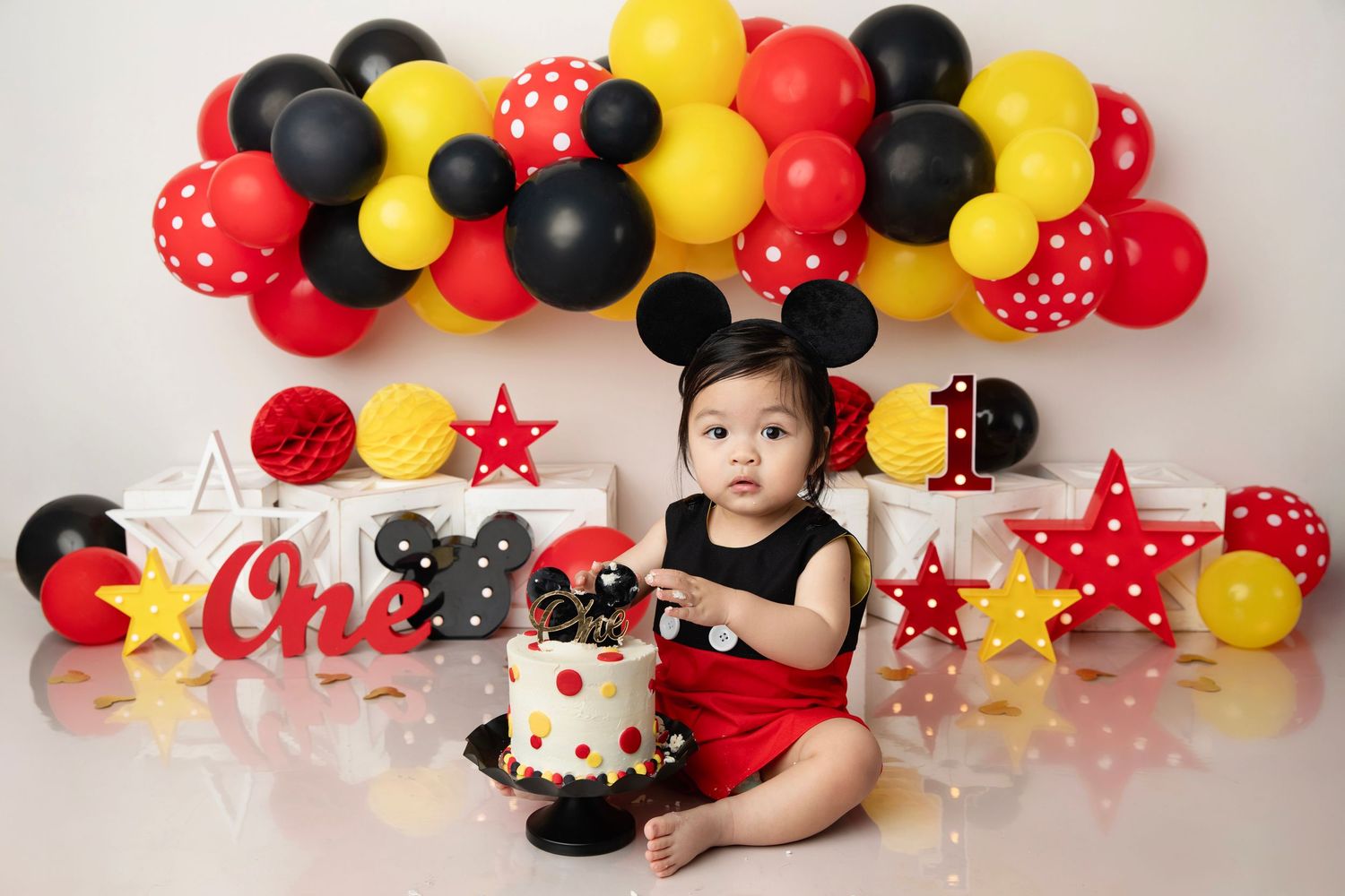 Red, black, and yellow balloon decorations with stars create a festive Mickey Mouse themed party backdrop.