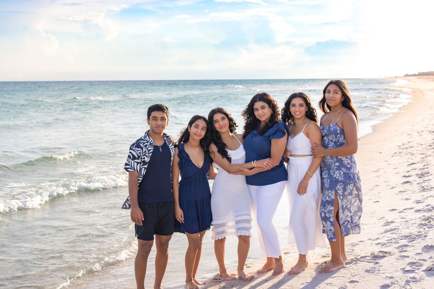 A group enjoys a relaxing stroll along a scenic beach with turquoise waves and white sand on a sunny day.