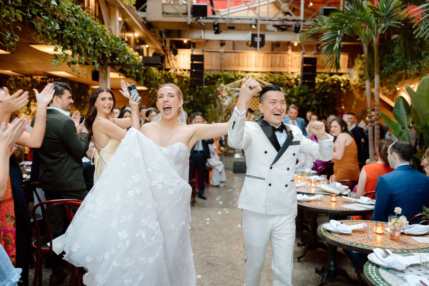A newlywed couple celebrates as they walk down the aisle, beaming with joy and surrounded by cheers and love.