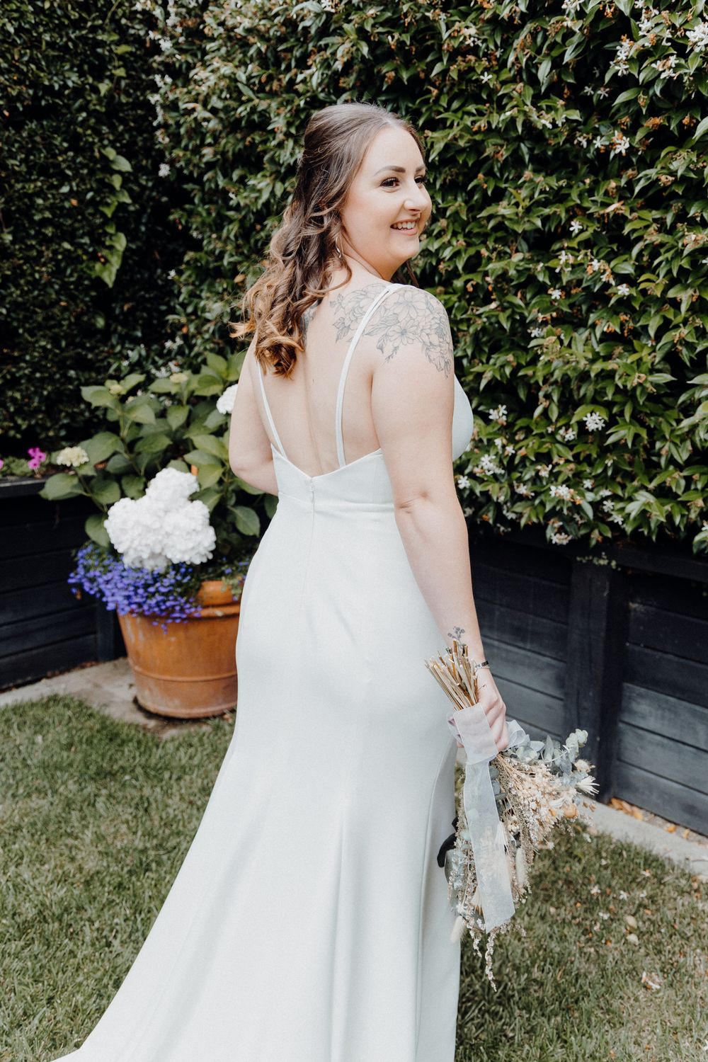 A bride in an elegant white wedding gown with lace cap sleeves, captured by Apertured Media Auckland Wedding Photographer.