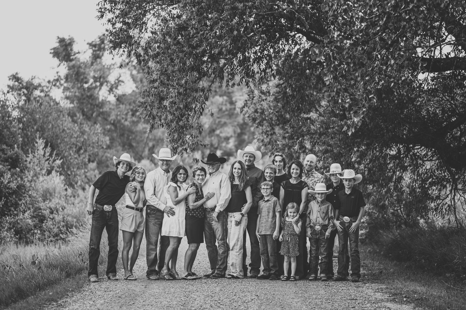 A large group standing together outdoors on a dirt path surrounded by trees in black and white photography.